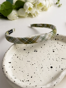 Close-up of green plaid fabric headband showing handmade label and premium textile texture