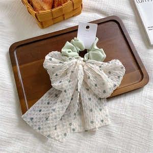 Détail d'un grand chouchou à fleurs avec des rubans en organza à pois verts frais