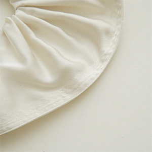 Detailed close-up of cream satin fabric hair scrunchie showing fine stitching and soft texture