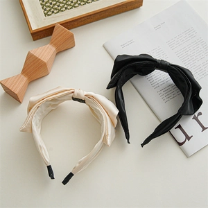 Detail of satin bow headbands in champagne and black colors with non-slip lining