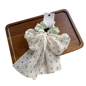 Chouchou en satin vert menthe à fleurs avec un grand nœud blanc sur carte de présentation