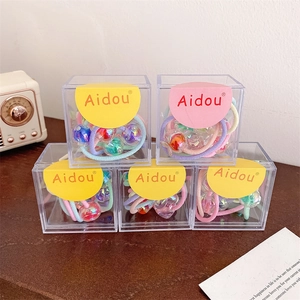 Détail de cinq boîtes d'élastiques à cheveux colorés avec perles pour petites filles