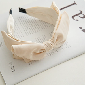 Close-up of beige fabric bow headband showing textured twill material on a magazine
