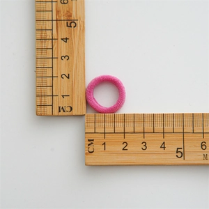 Close-up showing a 2cm pink mini elastic hair tie on a ruler for size reference