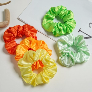 Macro shot of assorted colorful LED satin scrunchies showing smooth silk-like fabric texture