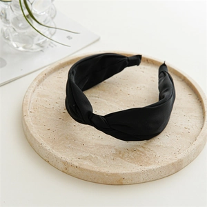 Dettaglio fascia per capelli in raso nero a treccia su vassoio di pietra elegante