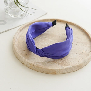 Dettaglio di un cerchietto in raso viola intrecciato su un vassoio di pietra elegante