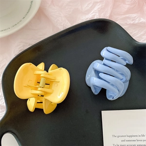 Détail de pinces à cheveux citrouille transparentes jaunes et bleues sur un plateau chic