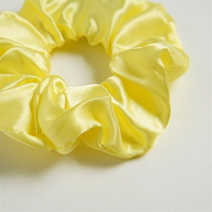 Detailed close-up of yellow satin LED scrunchie showing smooth silk texture and pleats