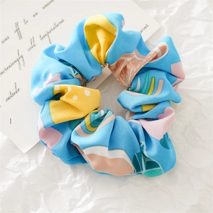 Close-up of sky blue fabric scrunchie with vibrant yellow and pink fruit pattern print