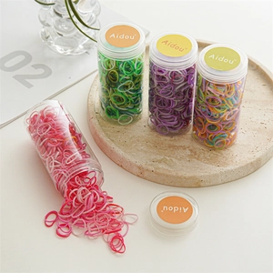 Set of four colorful high-elastic hair bands in transparent jars on a stone tray
