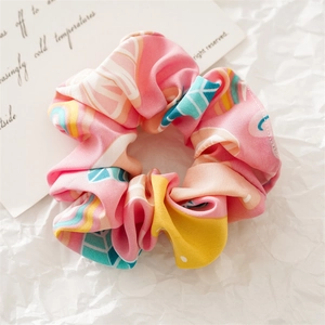 Detailed macro view of pink floral fabric scrunchie with colorful abstract geometric patterns