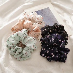 Detailed view of five colorful floral chiffon scrunchies on a soft white background
