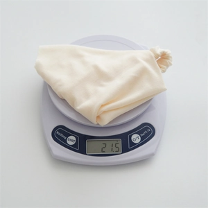Detailed top view of a lightweight beige cotton headscarf on a digital scale weighing 21.5g