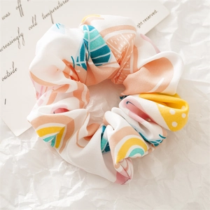 Detailed macro view of white fabric scrunchie with colorful leaf print on textured paper
