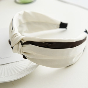 Detail of cross-knotted satin headband in cream white with dark brown contrast stripes