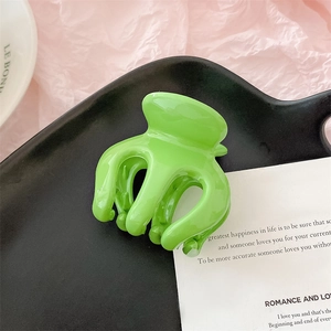 Vue détaillée d'une pince à cheveux vert vif en forme de citrouille sur plateau