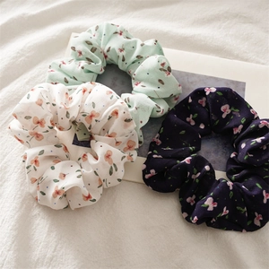 Detailed view of floral chiffon scrunchies in white, light green, and navy blue fabric