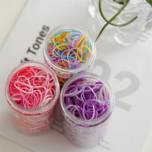 Detailed view of three transparent jars filled with pink, purple, and colorful elastic hair bands