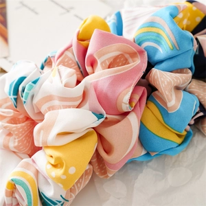 Close-up of fabric scrunchies with vibrant fruit and geometric patterns and soft folds