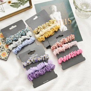 Détail d'un lot de chouchous en tissu fleuri et organza sur présentoir en carton