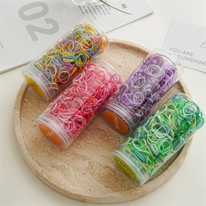 Detailed view of four jars with colorful high-elastic disposable hair rubber bands for styling