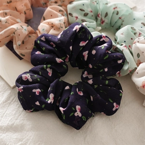 Floral chiffon scrunchies in navy blue, pink, mint green and white displayed on linen cloth