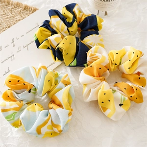 Detailed macro view of three fabric scrunchies featuring vibrant yellow lemon fruit patterns