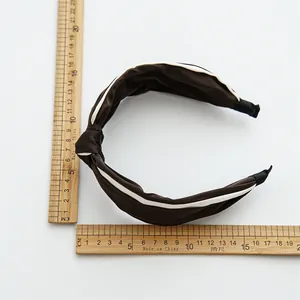 Macro view of knotted satin headband in coffee and white showing the 4.5cm width detail