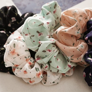 Detailed close-up of floral chiffon scrunchies in black, green, orange, white, and navy blue