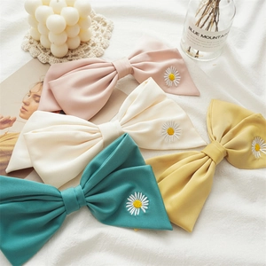 Close-up of four colorful chiffon hair bows with delicate daisy embroidery details