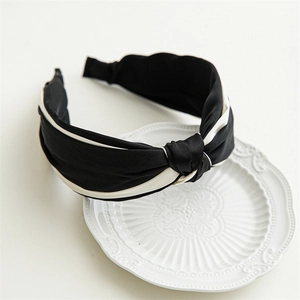 Detailed close-up of the black and white satin knotted headband on a white porcelain plate