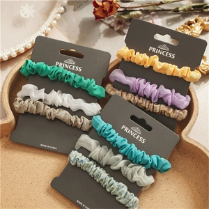 Detailed view of nine elastic scrunchies in pastel colors and patterns on a tray