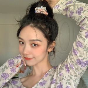Chouchou à fleurs présenté dans une coiffure assortie à un chemisier floral violet doux