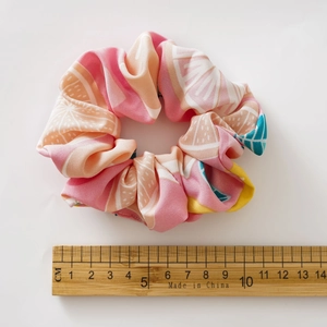 Detail showing an orange citrus print fabric scrunchie with measuring ruler for size guide