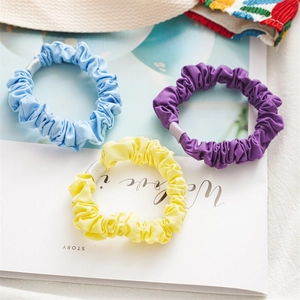 Detailed view of high-elastic fabric scrunchies in blue, purple, and yellow colors