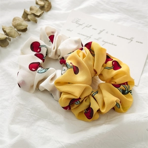Close-up of cream and yellow fruit pattern scrunchies with cherry prints on fabric