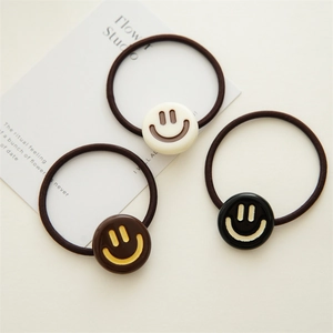 Detailed view of elastic hair ties featuring cute smiling face resin charms in three colors