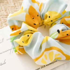 Detail of summer lemon print scrunchie made of light chiffon fabric on a rustic background