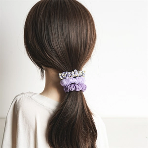 Set de chouchous à fleurs et violets porté en queue de cheval avec un style doux et minimaliste