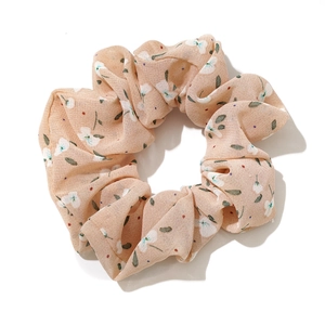 Floral chiffon scrunchie with delicate white flower patterns on beige fabric background