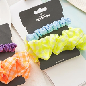 Close-up of fabric scrunchies in solid and checkered patterns on a display card