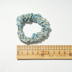 Chouchou bleu clair à motif floral d'environ 5cm de diamètre sur une règle graduée