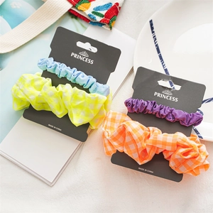 Detail of two-piece fabric scrunchie set with solid and plaid patterns on display card