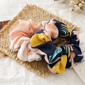 Detailed close-up of patterned fabric scrunchie with orange and abstract print