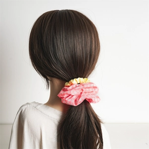 Pink plaid and solid yellow fabric scrunchies set for ponytail styling on beige background