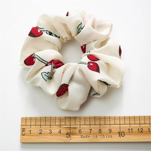 Elastic fabric scrunchie with red cherry print on cream background and 10cm diameter
