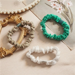 Three-piece fabric scrunchie set in green, white, and plaid with pleated design details