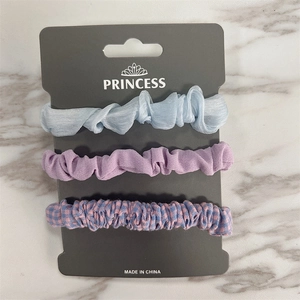 Detailed set of three assorted hair scrunchies in silk, matte purple, and plaid patterns