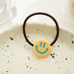 Detail of high-elasticity dark brown hair tie with a cute yellow smiley face charm